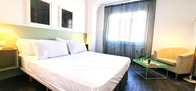 a bedroom with a bed and a chair and a window at Dionis Silence in Valencia