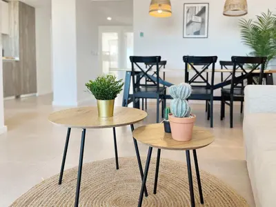 two tables in a living room with plants on them at Global Vacacional, Moderno apartamento de dos terrazas con vistas al mar y a la montaña in Canet de Berenguer