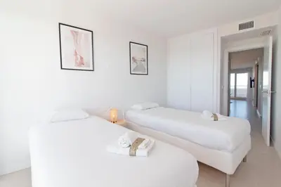 two beds in a room with white walls at Global Vacacional, Moderno apartamento de dos terrazas con vistas al mar y a la montaña in Canet de Berenguer