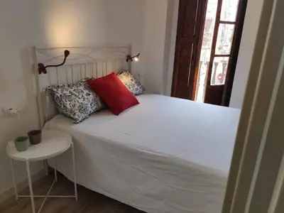a white bed with a red pillow and a table at Barcabanyal in Valencia
