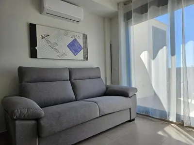 a couch in a living room with a window at Realrent Neo Mediterráneo in Barrio-Mar