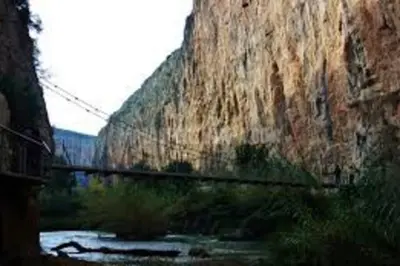 a train traveling past a large stone wall at Casa La Higuera in Chulilla