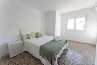 a white bedroom with a bed and a window at Precioso apartamento en altura in Altura