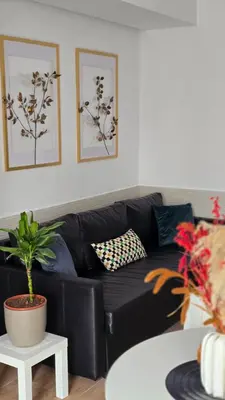 a black leather couch in a living room with a plant at Hlius Brand New Apartments in Valencia