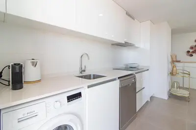 a white kitchen with a sink and a washing machine at Global Vacacional, Moderno apartamento con gran terraza y vistas al mar in Canet de Berenguer