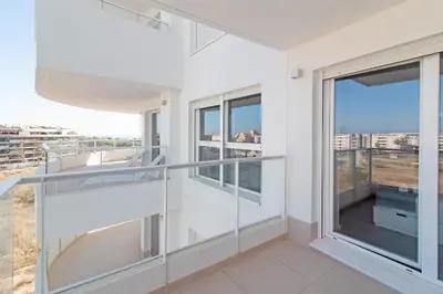 a balcony with glass railings in a white building at Global Vacacional, Moderno apartamento con gran terraza y vistas al mar in Canet de Berenguer