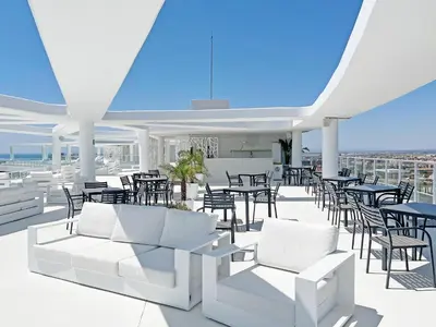 a patio with white furniture and tables and chairs at Global Vacacional, Moderno apartamento con gran terraza y vistas al mar in Canet de Berenguer