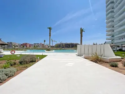 a walkway leading to a pool with palm trees at Global Vacacional, Moderno apartamento con gran terraza y vistas al mar in Canet de Berenguer