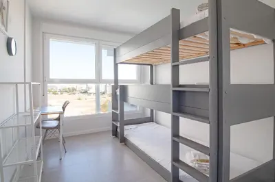 a room with bunk beds and a table and a chair at Global Vacacional, Moderno apartamento con gran terraza y vistas al mar in Canet de Berenguer