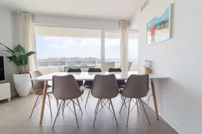 a dining room with a table and chairs and a large window at Global Vacacional, Moderno apartamento con gran terraza y vistas al mar in Canet de Berenguer