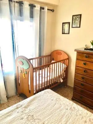 a baby crib in a bedroom with a dresser and a window at Spacious apartment in Tavernes de la Valldigna with sea view in El Brosquil