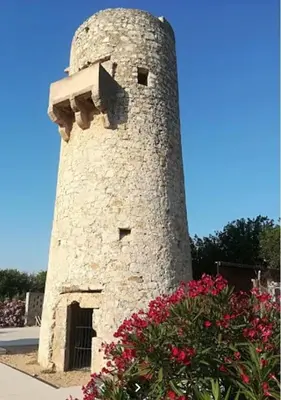 a stone lighthouse with flowers in front of it at Spacious apartment in Tavernes de la Valldigna with sea view in El Brosquil