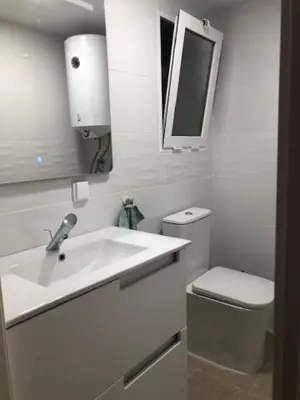 a white bathroom with a sink and a toilet at A 50 m de la plage in Cullera