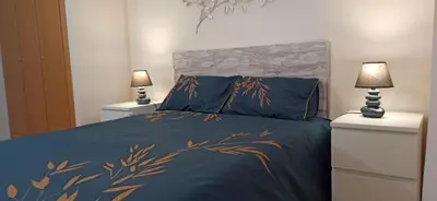 a bedroom with a bed with blue sheets and two lamps at Apartamento Aguamarina - Playa Moncofa in Moncófar