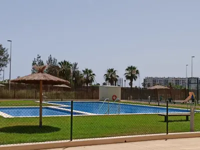 a large swimming pool with an umbrella and grass at Apartamento Aguamarina - Playa Moncofa in Moncófar