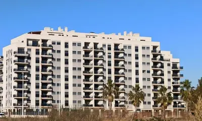 a large white building with palm trees in front of it at Apartamento Aguamarina - Playa Moncofa in Moncófar