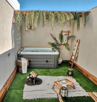 a small backyard with a tub and grass at Suite con Jacuzzi en la montaña. in Llombay