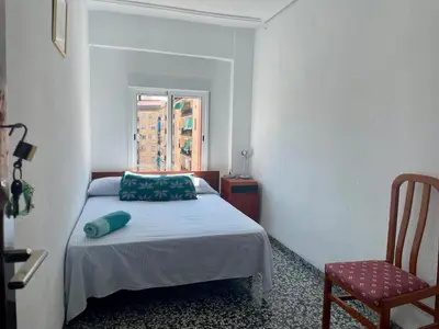 a small bedroom with a bed and a chair at private room in shared apartment Valencia WorkStay in Valencia