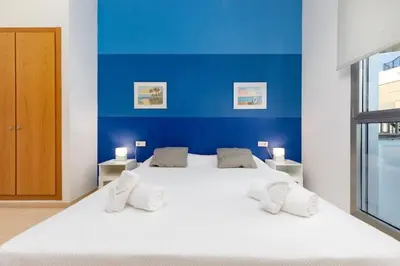 a bedroom with a large white bed with a blue wall at luxury sea view apartment with 2 rooms in Valencia