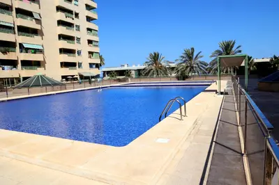 a large swimming pool in front of a building at Apartamento dos habitaciones primera línea de playa in Valencia