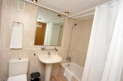 a bathroom with a sink and a toilet and a mirror at Apartamento dos habitaciones primera línea de playa in Valencia