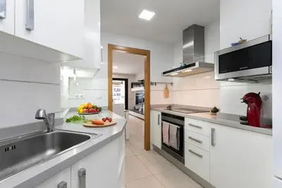 a white kitchen with a sink and a counter top at Veramar Beach Apartment in Valencia