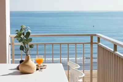a table with a vase and a glass of orange juice on a balcony at Almar Collection Cullera AR in Cullera