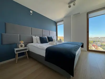 a bedroom with a large bed with a blue wall at Colina del Sol Penthouse Horizonte in Cullera