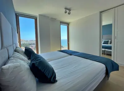 a bedroom with a large bed with large windows at Colina del Sol Penthouse Horizonte in Cullera