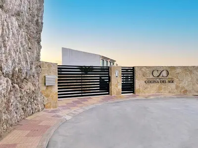 a building with a gate and a stone wall at Colina del Sol Penthouse Horizonte in Cullera