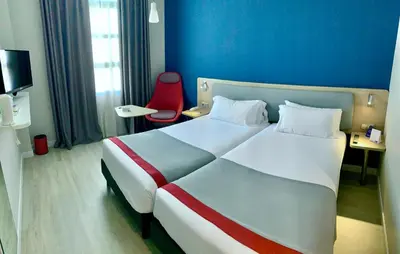a hotel room with a large bed and a red chair at Holiday Inn Express Ciudad de las Ciencias by IHG in Valencia