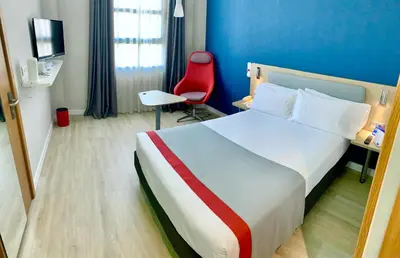 a hotel room with a bed and a red chair at Holiday Inn Express Ciudad de las Ciencias by IHG in Valencia