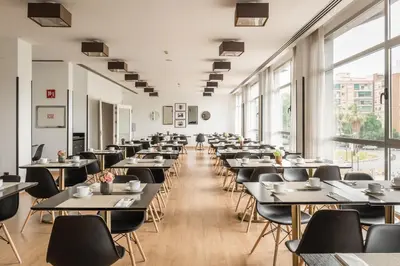 a dining room with tables and chairs and windows at Hotel Medium Valencia in Valencia