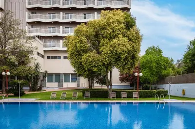 a swimming pool with chairs in front of a building at Hotel Medium Valencia in Valencia