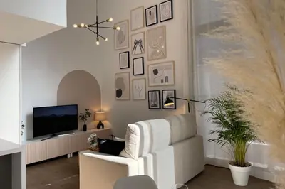 a living room with a white chair and a tv at SingularStays Arena in Valencia