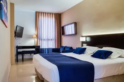 a hotel room with a large bed and a desk at Hotel Ignacio - PalomarGroup in Chiva