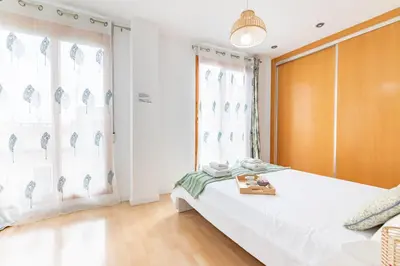 a bedroom with a bed with white sheets and windows at Penthouse Duplex in a 4 floors spanish house -8 min to center by Metro in Valencia