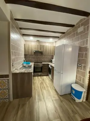 a kitchen with a white refrigerator and wooden floors at La Carchata in Siete Aguas