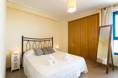 a bedroom with a large white bed with towels on it at ApartUP Patacona Orchard Views in Valencia