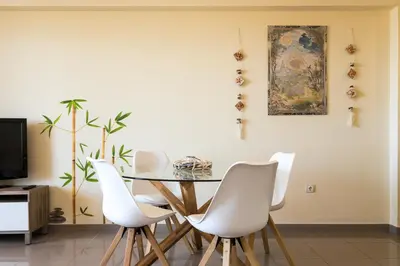 a dining room with a table and white chairs at ApartUP Patacona Orchard Views in Valencia