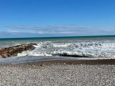 a beach with a rocky shoreline and the ocean at Apartamento Grao de Moncofar REF. 041 in Moncófar