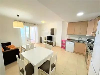 a living room with a white table and a kitchen at Apartamento Grao de Moncofar REF. 041 in Moncófar