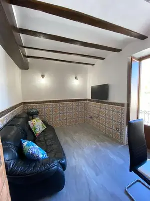 a living room with a black leather couch and a flat screen tv at La carchata 1 in Siete Aguas