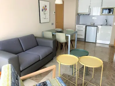 a living room with a couch and two tables and a kitchen at Apartamentos Plaza Picasso in Valencia