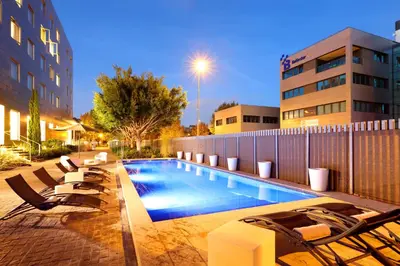 a swimming pool with lounge chairs next to a building at Exe Puerto de Sagunto in Puerto de Sagunto