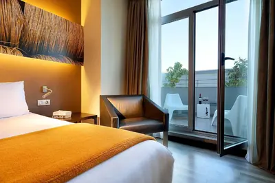 a hotel room with a bed and a chair and a window at Exe Puerto de Sagunto in Puerto de Sagunto