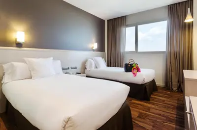 a hotel room with two beds and a window at AZZ Valencia Táctica Hotel in Paterna