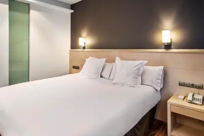 a bedroom with a large bed with white sheets and pillows at AZZ Valencia Táctica Hotel in Paterna