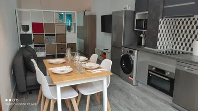 a kitchen with a wooden table and white chairs at APARTMENTSUITESPAIN PLAYA - UNIVERSIDADes in Valencia