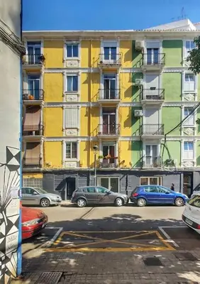 a yellow building with cars parked in a parking lot at 7P céntrico piso con encanto in Valencia